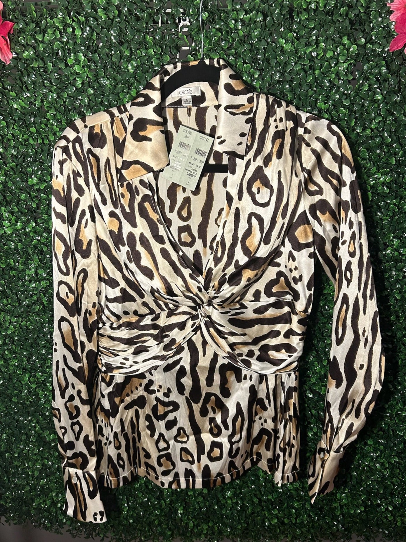Leopard print blouse with a tag on a green leafy background