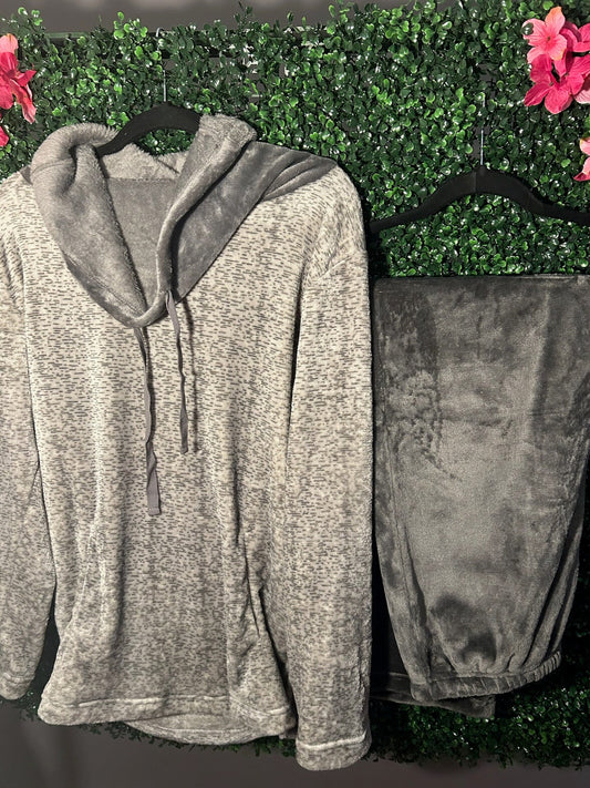 Gray hoodie and pants on hangers against a green leafy background with pink flowers.