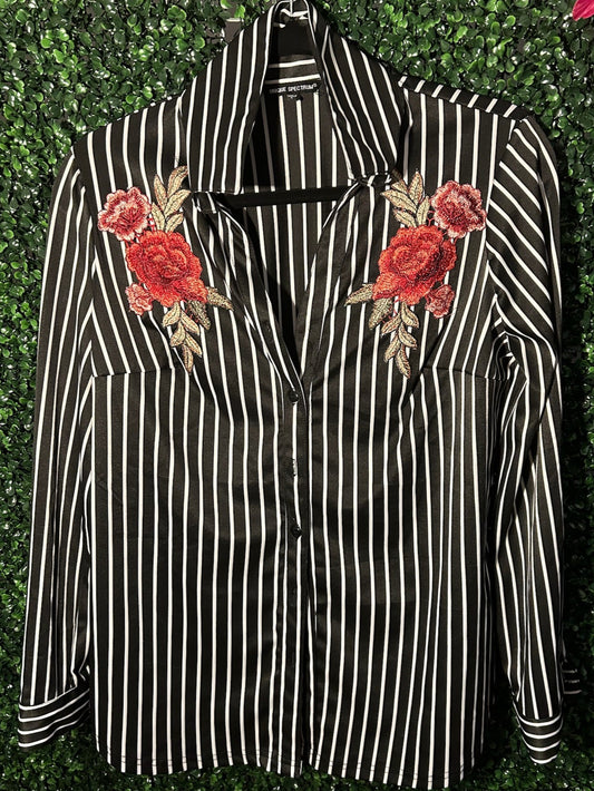 Black and white striped shirt with floral embroidery on a green leafy background