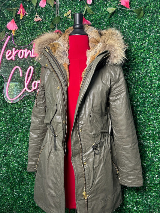 Green parka coat on a mannequin against a green textured wall with 'Veron Clo' branding.
