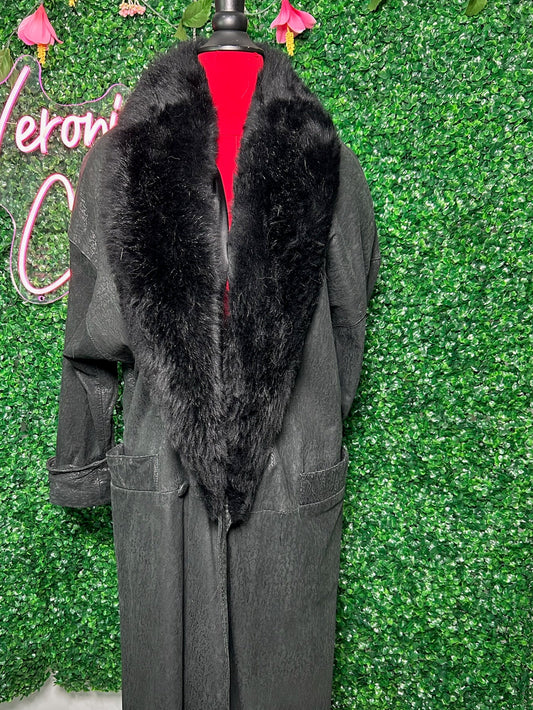 Gray coat with black fur collar on a mannequin against a green leafy background.